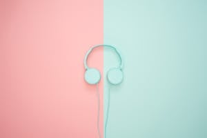 Minimalist headphones on a pink and mint background, artistic and modern.
